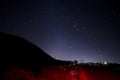 Beautiful night landscape of stars at sky and mountain silhouette near road with car trails. Road in the mountains under a starry Royalty Free Stock Photo