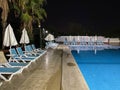 Beautiful night swimming pool with umbrellas and deck chairs and palm trees in a hotel on vacation in a tourist warm tropical Royalty Free Stock Photo