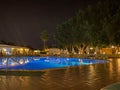 Beautiful night swimming pool with umbrellas and deck chairs and palm trees in a hotel on vacation in a tourist warm tropical Royalty Free Stock Photo