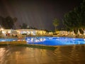 Beautiful night swimming pool with umbrellas and deck chairs and palm trees in a hotel on vacation in a tourist warm tropical Royalty Free Stock Photo