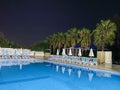 Beautiful night swimming pool with umbrellas and deck chairs and palm trees in a hotel on vacation in a tourist warm tropical Royalty Free Stock Photo