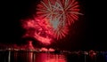 Beautiful night view of red glowing fireworks in the black sky over illuminating skyline city Royalty Free Stock Photo