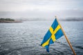 Beautiful nordic archipelago summer view of land and island against sea and hazy horizon with Swedish flag in the foreground. Royalty Free Stock Photo