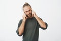 Beautiful nordic man with trendy haircut and beard being tired, massaging temples with fingers trying to concentrate on Royalty Free Stock Photo