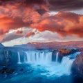 Mystical morning view of Godafoss waterfall with red clouds above.