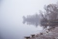 A beautiful Norwegian autumn scenery. Misty morning on a lake. Water flowing over the dam, waterfall. Royalty Free Stock Photo