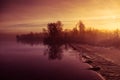 A beautiful Norwegian autumn scenery. Misty morning on a lake. Water flowing over the dam, waterfall. Royalty Free Stock Photo