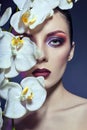 Beautiful Nude woman with a branch of white Orchid in her hands, bright contrasting makeup on the eyes and lips. Contrasting colo Royalty Free Stock Photo