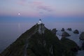 Nugget Point Lighthouse. Pink sunset sky with the moon, South Island, New Zealand Royalty Free Stock Photo