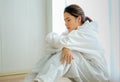 Beautiful nurse or clinician with body protective suit sit near glass window with tire and sad emotion after work with covid