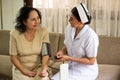 Nurse doing pressure measuring for female patient in the room