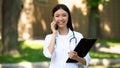 Beautiful nurse talking smartphone with patient at rehabilitation center park Royalty Free Stock Photo