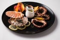 Beautiful octopus dish garnished with sliced lemons and pomegranates on a black plate Royalty Free Stock Photo