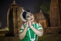 Beautiful Odissi dancer looks at the mirror during the Odissi dance recital against the backdrop of Mukteshvara Temple sculpture.