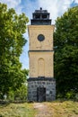 Beautiful old ancient yellow stone bell tower. Summer nature with green leaf trees.