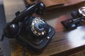 Beautiful old black telephone with a manual dial standing on a wooden table. Vintage communication concept. Outdated Royalty Free Stock Photo