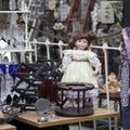 beautiful old doll among household goods at a flea market