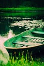 A beautiful old fishing boat is floating along a grassy riverbank on a sunny summer day. Nostalgia, tranquility, and the peaceful