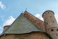 A beautiful old fortress church made of red brick against a blue sky background. Beautiful tiled roof of a medieval castle and Royalty Free Stock Photo