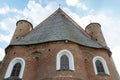 A beautiful old fortress church made of red brick against a blue sky background. Beautiful tiled roof of a medieval castle and Royalty Free Stock Photo