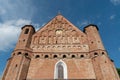 A beautiful old fortress church made of red brick against a blue sky background. A high impregnable fortress with iron crosses on