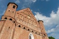 A beautiful old fortress church made of red brick against a blue sky background. A high impregnable fortress with iron crosses on