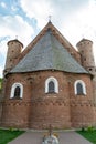 A beautiful old fortress church made of red brick against a blue sky background. Beautiful tiled roof of a medieval castle and Royalty Free Stock Photo