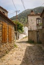 Beautiful old street paved with stones, turkish traditional village houses on both sides, green mountains in the background - Royalty Free Stock Photo