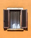 Beautiful old window frame with brown wooden shutters and bright yellow wall. Rural or antique window frame. Design element.