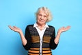 Beautiful old woman in stylish clothes is shrugging shoulders. Royalty Free Stock Photo