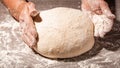 Beautiful and old women`s hands knead the dough from which they will then make bread, pasta or pizza. A cloud of flour flies Royalty Free Stock Photo