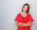 Beautiful older woman with arms crossed against gray background Royalty Free Stock Photo