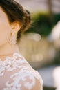 Beautiful openwork precious earring in the ear of the bride in a white dress. Close-up