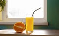 Beautiful orange fruit and glass of juice with iron nont plastic tubule near the window on table lifestile picture