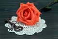 Beautiful orange rose on an antique doilie and vintage keys.