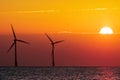 Beautiful orange sunrise behind offshore wind farm turbines Royalty Free Stock Photo