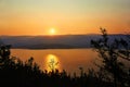 Beautiful orange sunset over the mountains in summer. The rays of the setting sun are reflected in Lake Baikal Royalty Free Stock Photo