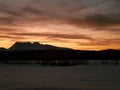 Beautiful orange sunset over snowy mountain peak, field and settlement in northern norway Royalty Free Stock Photo