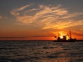 Beautiful orange sunset on sea water. Transport ship on the dock in the evening on seacoast. Shipping logistic by sea Royalty Free Stock Photo