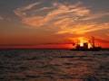 Beautiful orange sunset on sea water. Transport ship on the dock in the evening on seacoast. Shipping logistic by sea Royalty Free Stock Photo