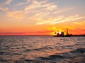 Beautiful orange sunset on sea water. Transport ship on the dock in the evening on seacoast. Shipping logistic by sea Royalty Free Stock Photo