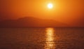 beautiful orange tone sunset sunrise over the sea or ocean, big sun above mountain hill, sun specular reflection in water Royalty Free Stock Photo