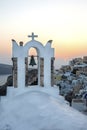 Arch with a bell, white houses and church with blue domes in Oia or Ia at golden sunset, island Santorini, Greece. - Immagine Royalty Free Stock Photo