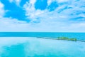 Beautiful outdoor infinity swimming pool in hotel resort with sea ocean view and white cloud blue sky Royalty Free Stock Photo