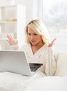 Beautiful outraged woman sitting on the sofa using a laptop