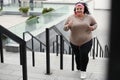 Beautiful overweight woman running up stairs