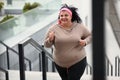 Beautiful overweight woman running up stairs