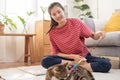 Beautiful owner kitten asian young woman, girl happy in free time in casual holding toy playing with lovey cat, sitting on carpet