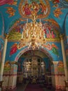 Beautiful painted walls and ceiling inside the Capriana Monastery. Golden chandelier suspending with glowing lights. Different