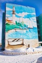 Beautiful painting of graffiti on the facade of a five-storey building in Russia. Winter. Drawing sea, lighthouse yacht, boat
